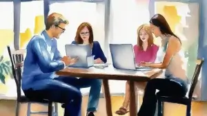 a group of people sitting at a table with laptops